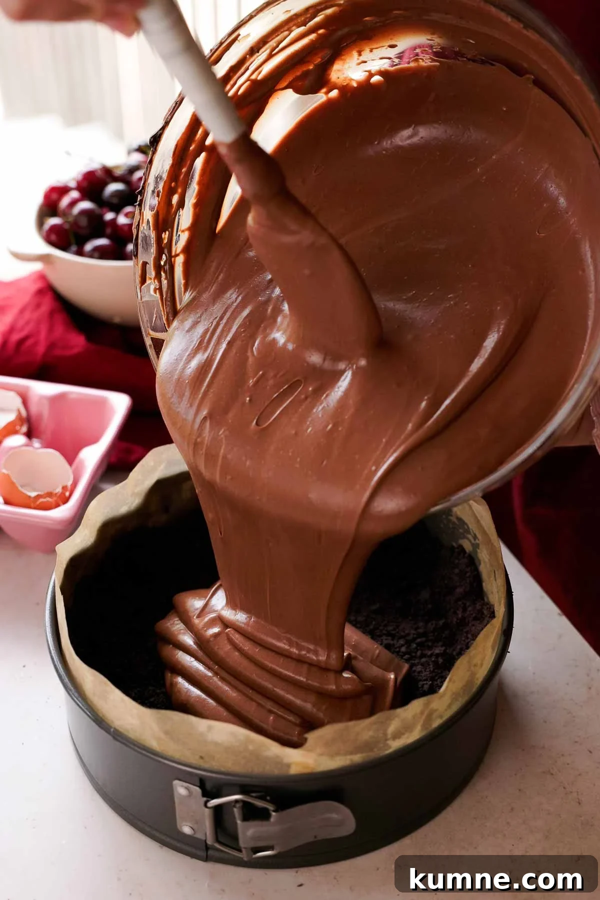 pouring chocolate cheesecake batter into oreo cheesecake crust