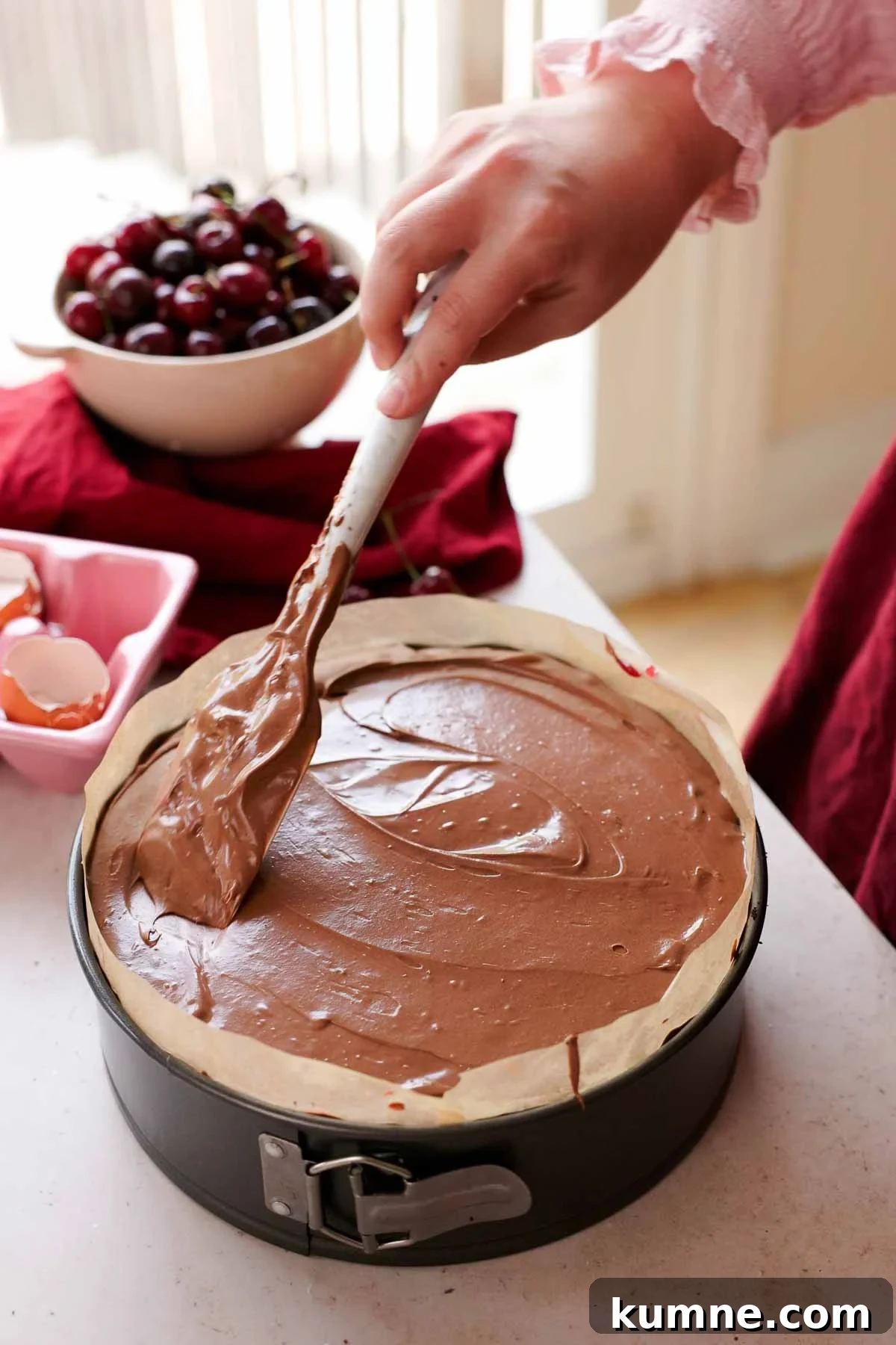 smoothing the top of chocolate cherry cheesecake with a spatula
