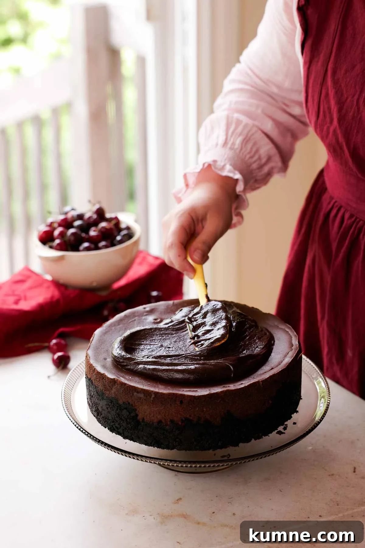 smoothing chocolate ganache onto black forest cheesecake