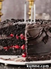 black velvet cake with a piece cut out and black frosting