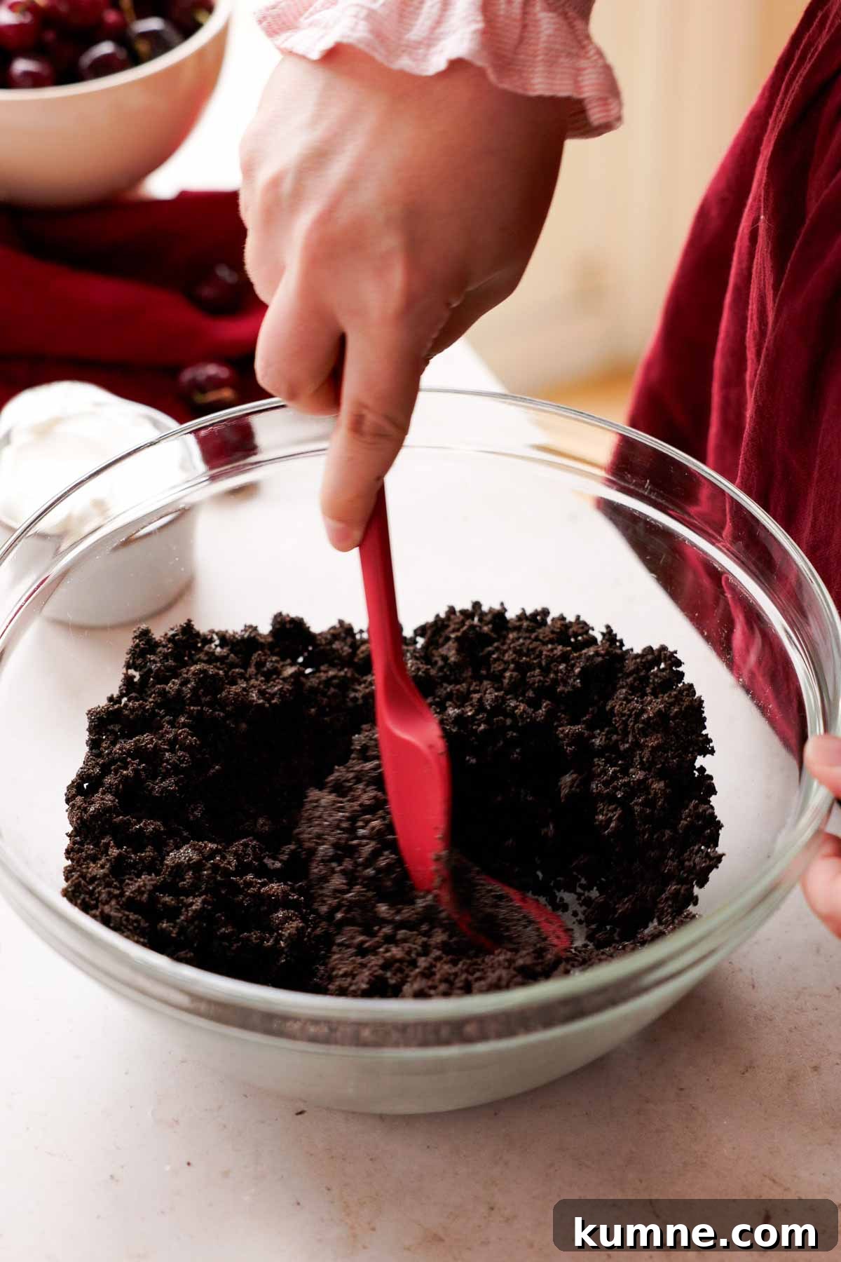 stirring crushed oreos with melted butter in large glass bowl