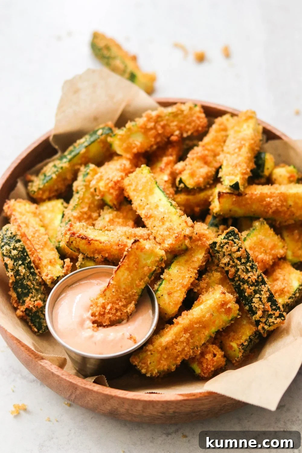 Keto Air Fryer Zucchini Fries Recipe for Low-Carb Snacks 2 air fryer zucchini fries in a brown bowl next to a small container of dipping sauce