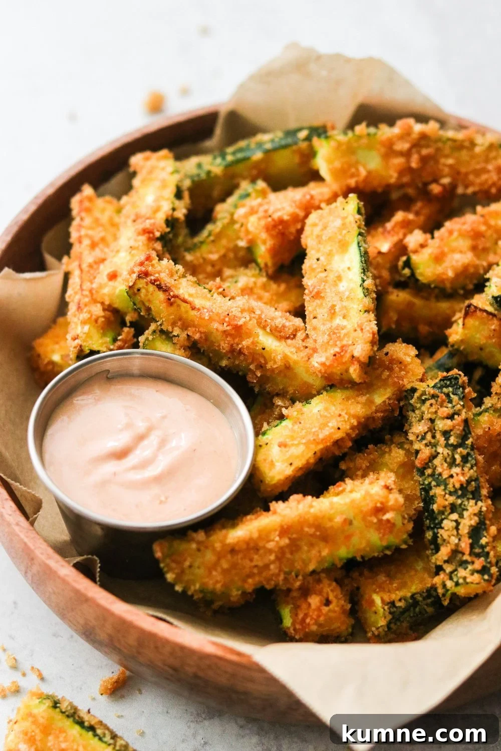 Keto Air Fryer Zucchini Fries Recipe for Low-Carb Snacks 6 a side view of zucchini sticks fried with pork panko with a silver bowl of dipping sauce nearby.