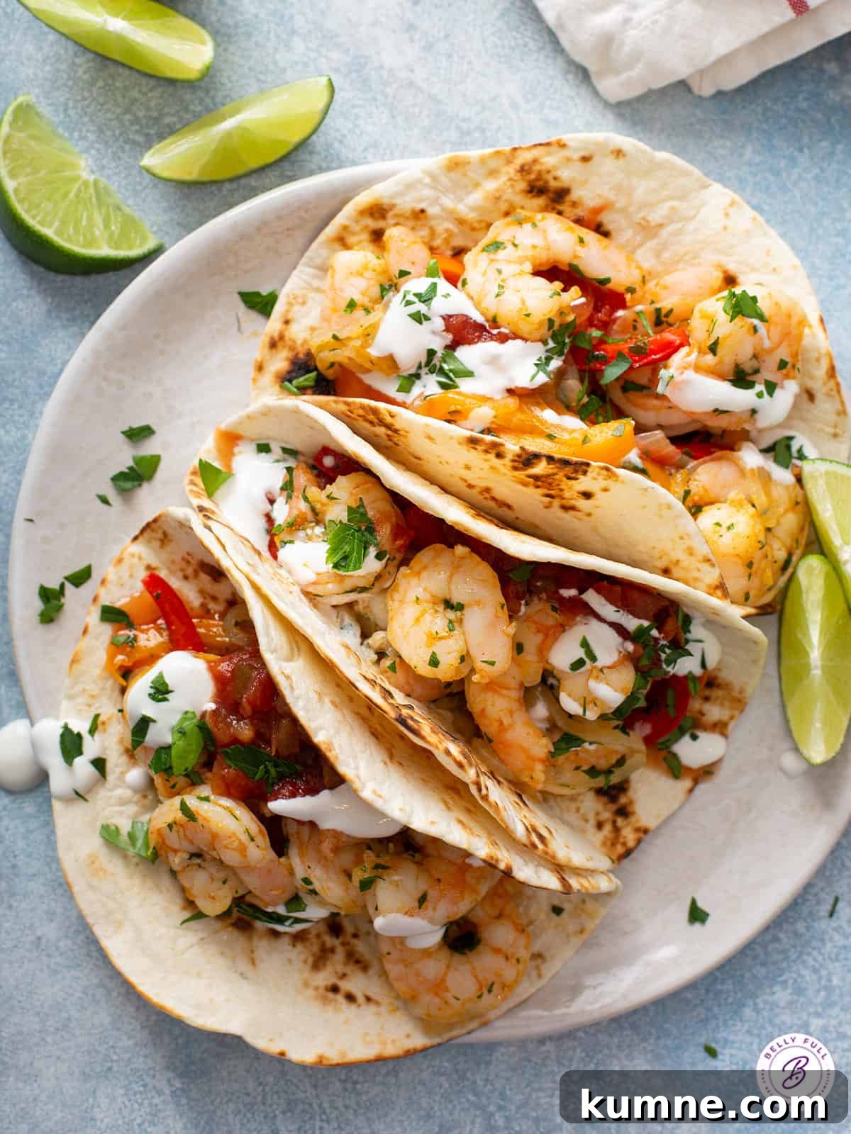 Sizzling Shrimp Fajitas Recipe for Quick Weeknight Dinner 8 3 shrimp fajitas on a white plate with lime wedges.
