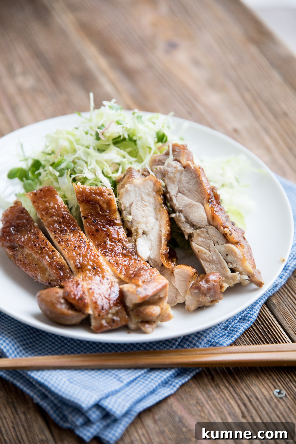 cross section of teriyaki chicken on a white plate with crispy skin and glossy glaze