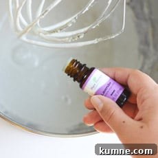 lavender essential oil being added to a kitchenaid mixer of homemade diaper rash cream