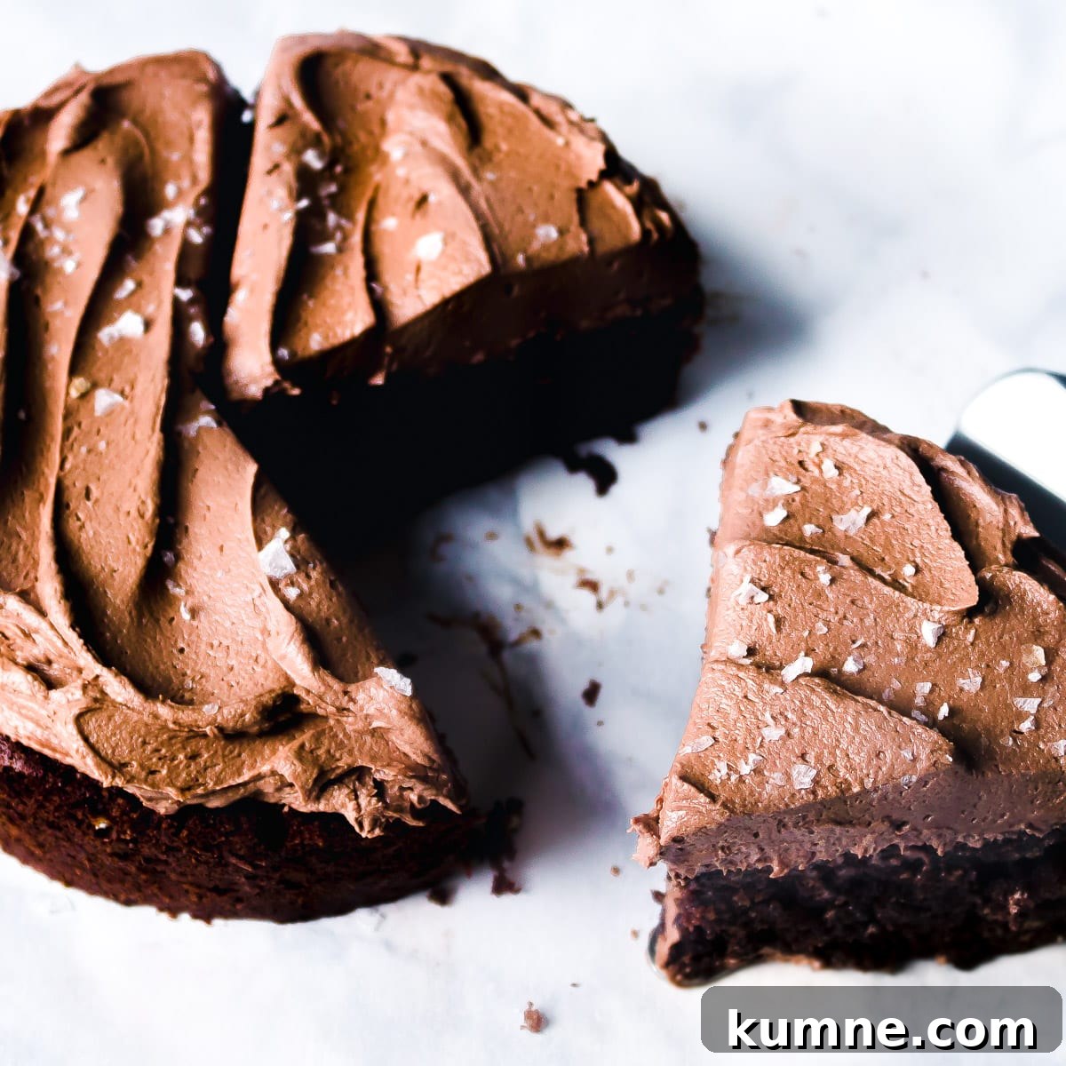 mini chocolate cake frosted with chocolate buttercream with a slice cut out of it