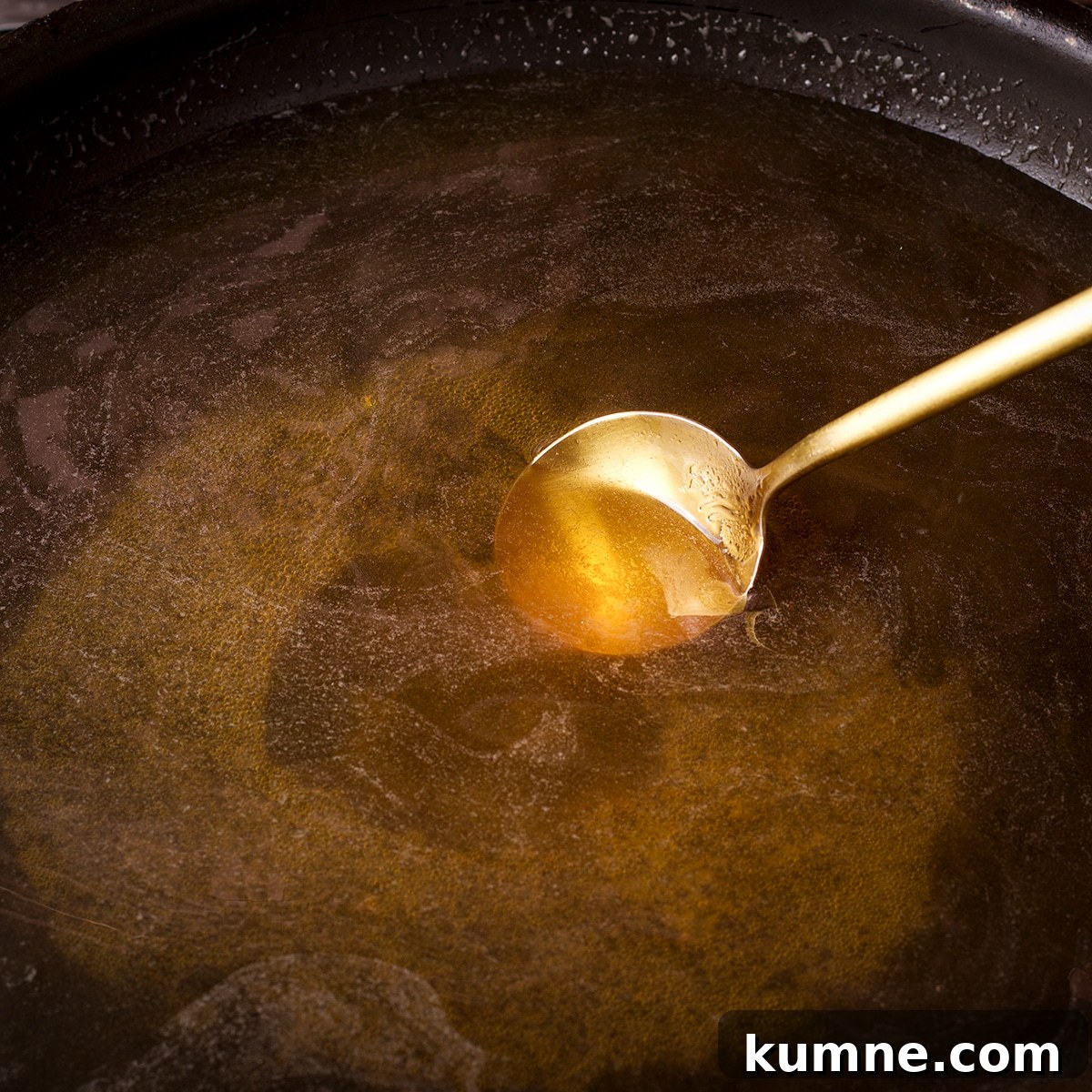 Stirring sugar and water in a skillet while it cooks on the stovetop.
