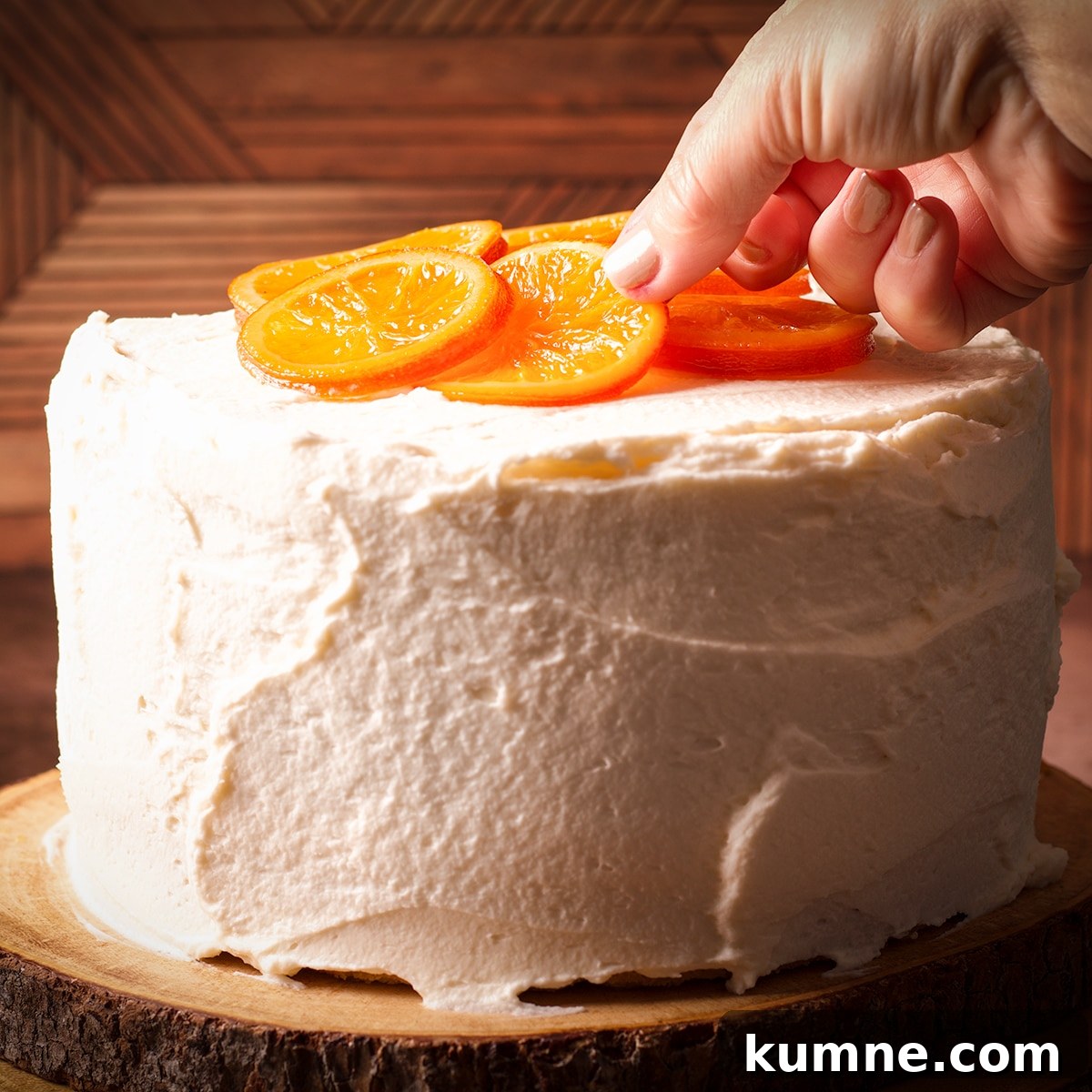 Laying candied orange slices on top of a three-layer orange olive oil cake covered in mascarpone frosting.