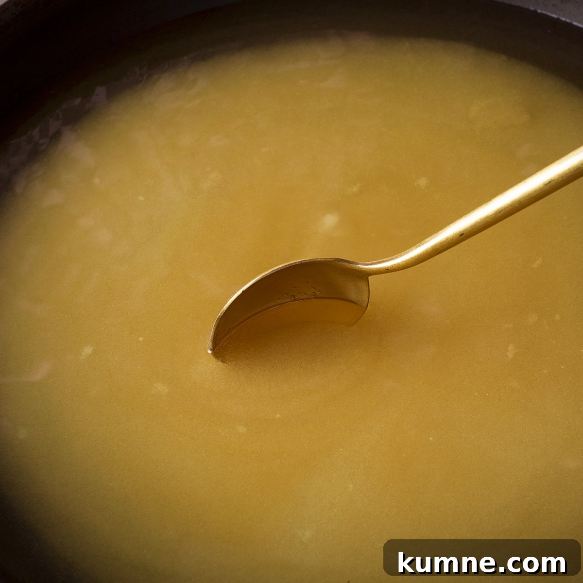 Using a spoon to stir simple syrup while it simmers on the stovetop.