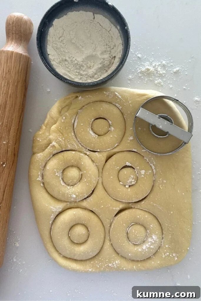 Cutting out sourdough donuts using a donut cutter.