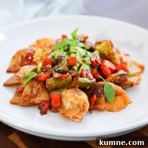Side shot of stir fry with wontons and vegetables and thai basil.
