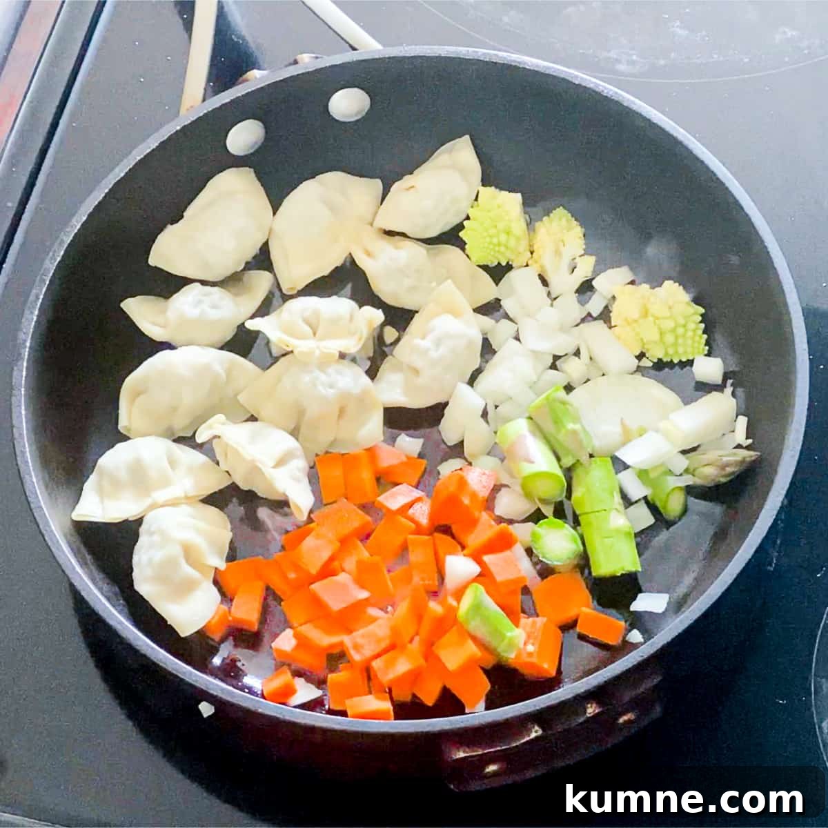 Wontons and vegetables browning in a pan