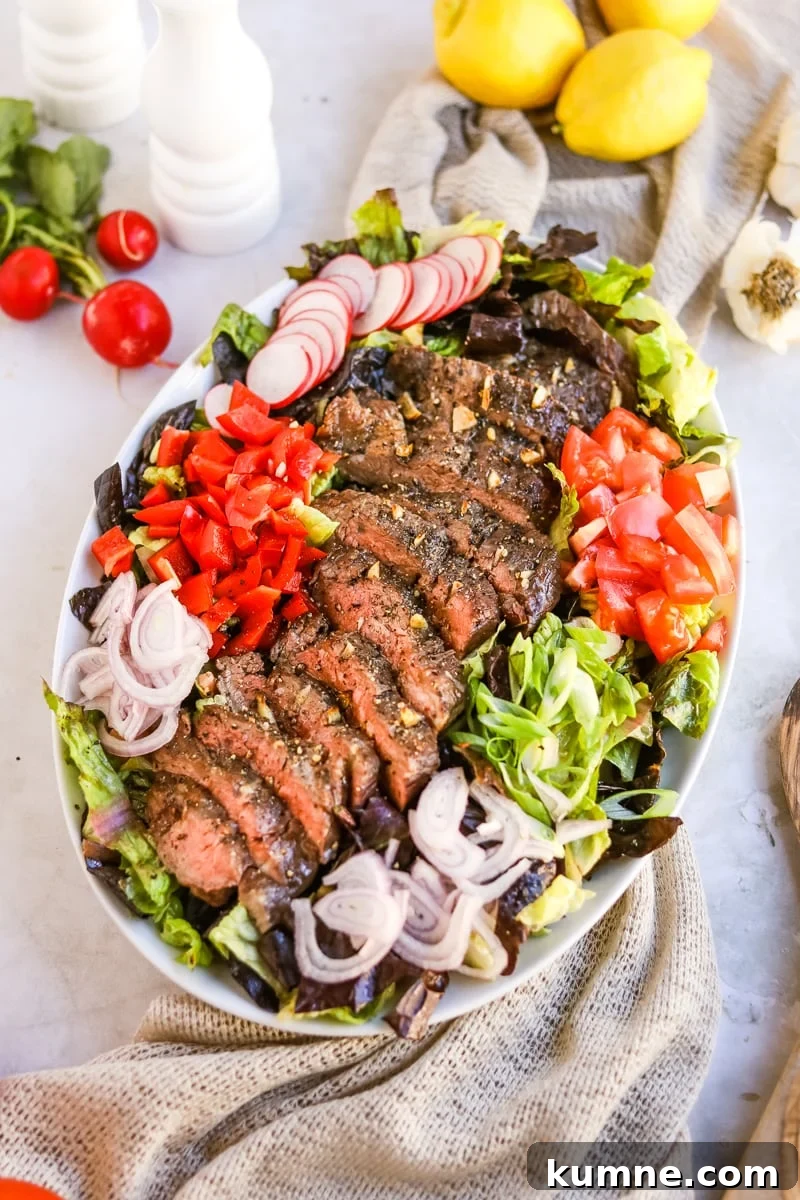 Flank steak salad with lettuce, radish, tomato, bell pepper, shallot, green onion, and a balsamic dressing.