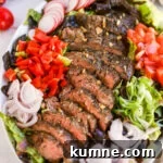 Flank steak salad with lettuce, radish, tomato, bell pepper, shallot, green onion, and a balsamic dressing.