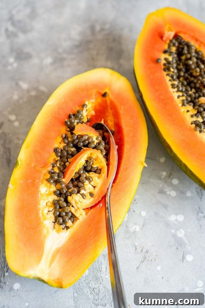 Spoon scooping the seeds out of a papaya.