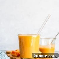 Healthy Creamy Vegan Papaya Smoothie on a cutting board with some chopped pieces of papaya.