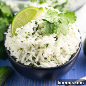 Chipotle-Style Cilantro Lime Rice Recipe for Flavorful Sides 4 White chipotle lime rice garnished with a fresh lime wedge and sprig of cilantro in a black bowl on a blue wood background