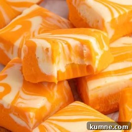 Close up of orange creamsicle fudge with creamy white swirls and one piece with a bite taken out