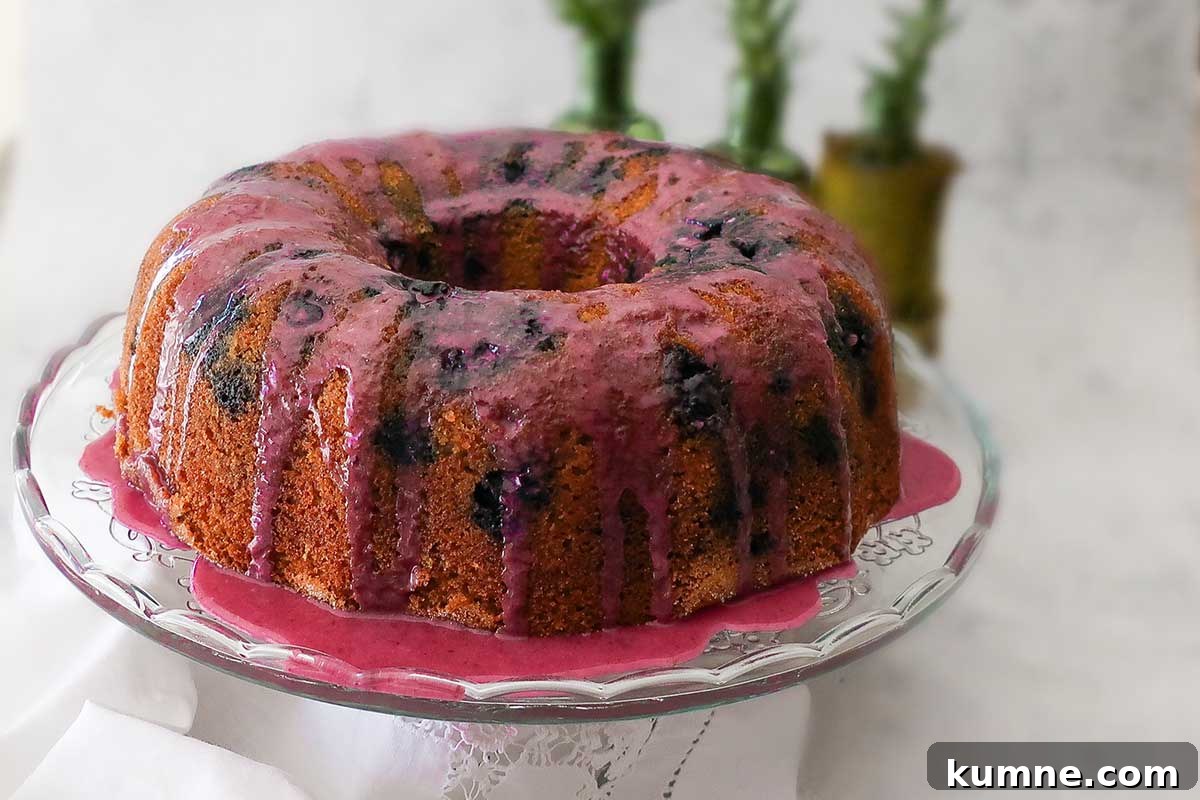 20+ Gluten-Free Blueberry Recipes for Delightful Desserts and Snacks 7 whole blueberry bundt cake on a cake platter drizzles with blueberry orange glaze