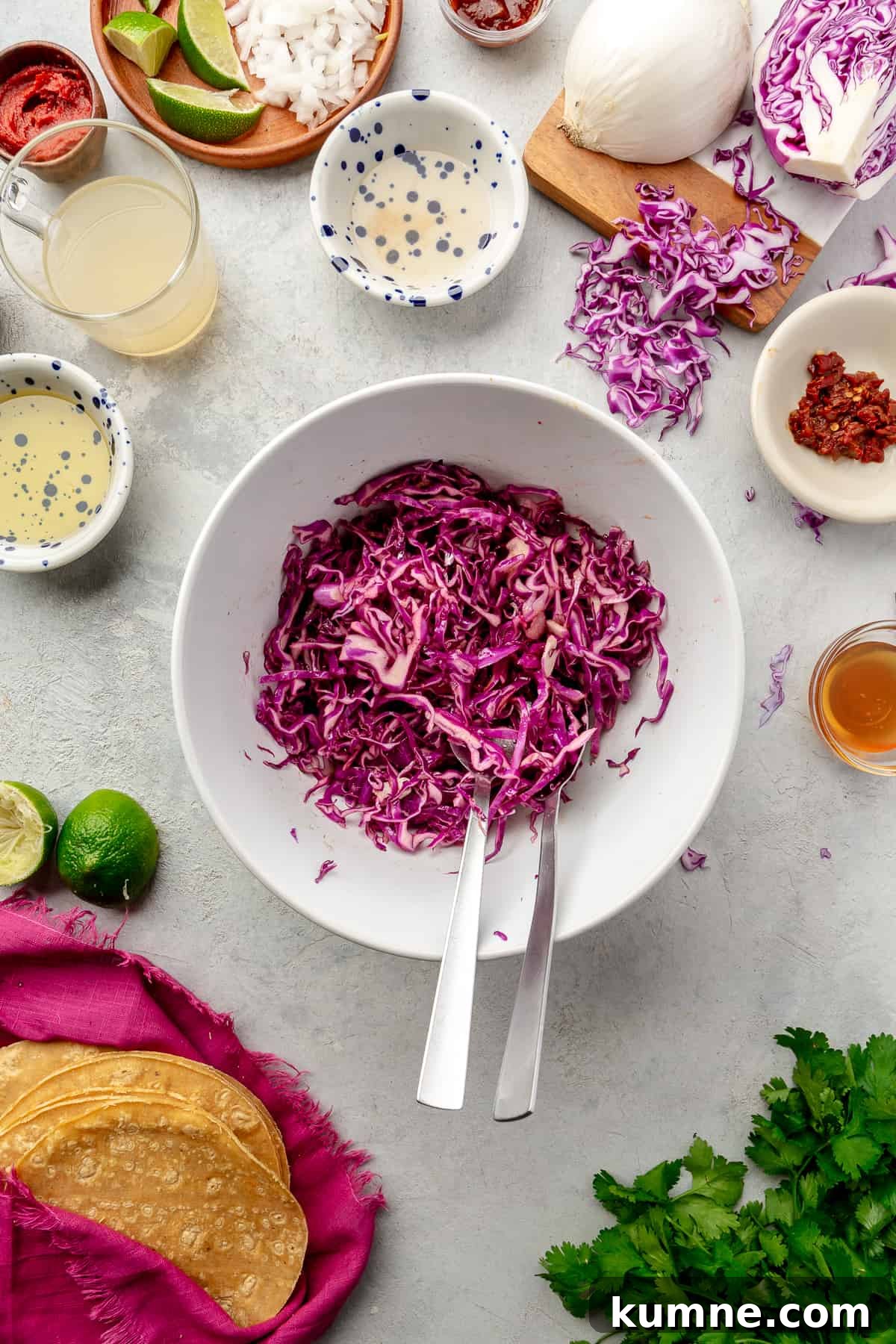 Sticky Chipotle Chicken Tacos with Smoky Lime Slaw 5 Slaw in a large white bowl with ingredients scattered around.