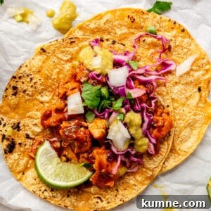 A Saucy Chipotle Chicken Taco on a piece of parchment paper. Lime wedges scattered around.