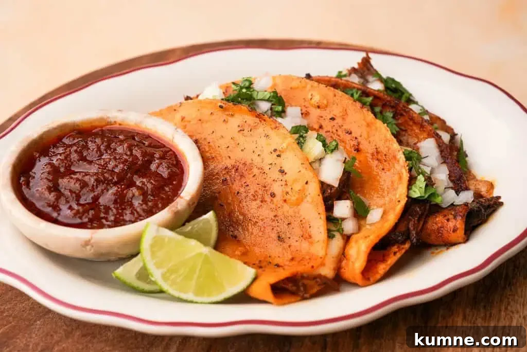 birria tacos recipe Crispy birria tacos filled with shredded beef and cheese, served with consommé for dipping and lime wedges on the side.