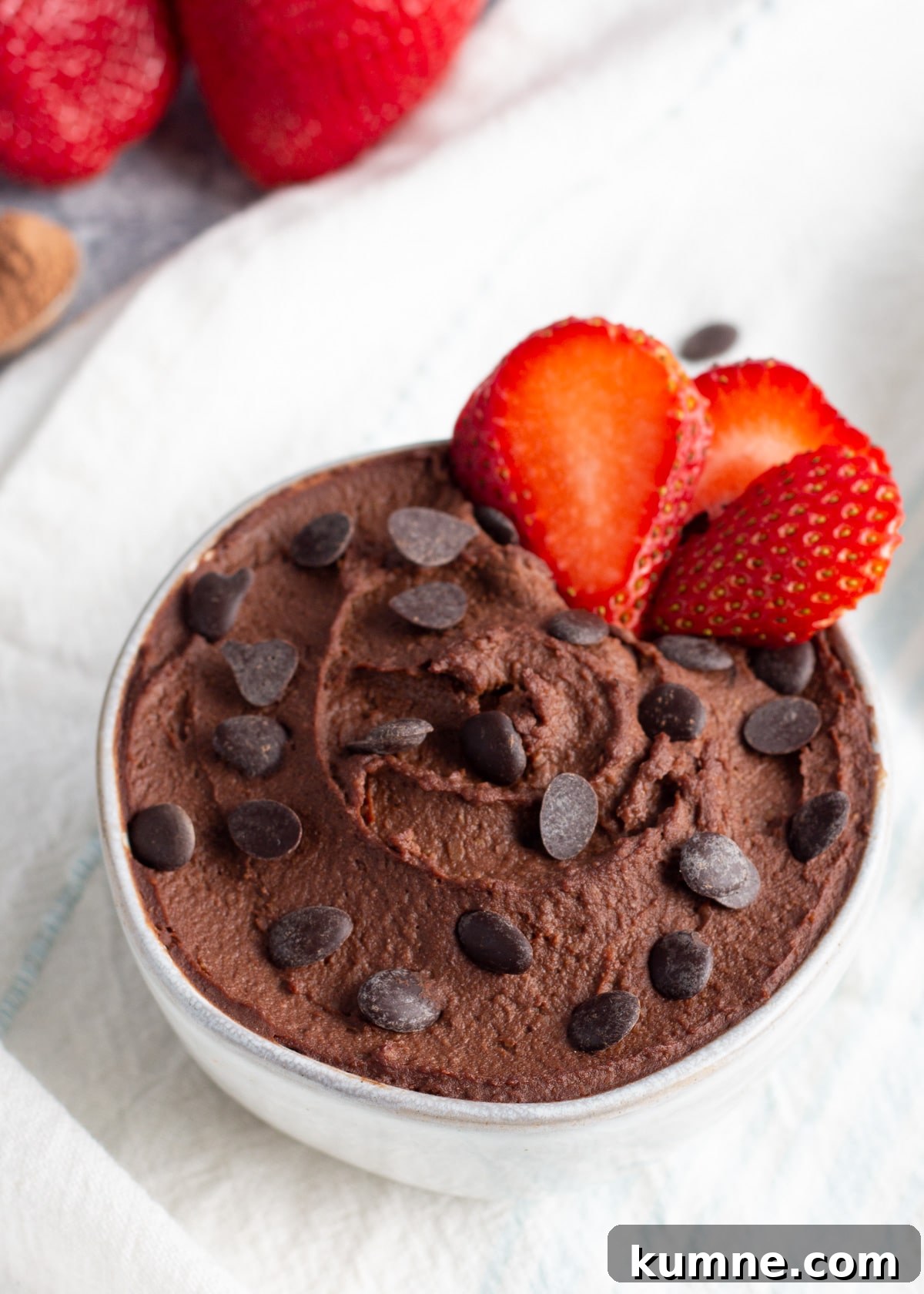 Dark chocolate hummus close-up picture with chocolate chips and strawberry.