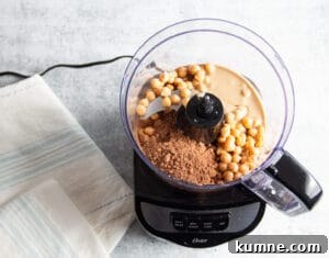 Picture of a food processor with all ingredients inside to make chocolate hummus.