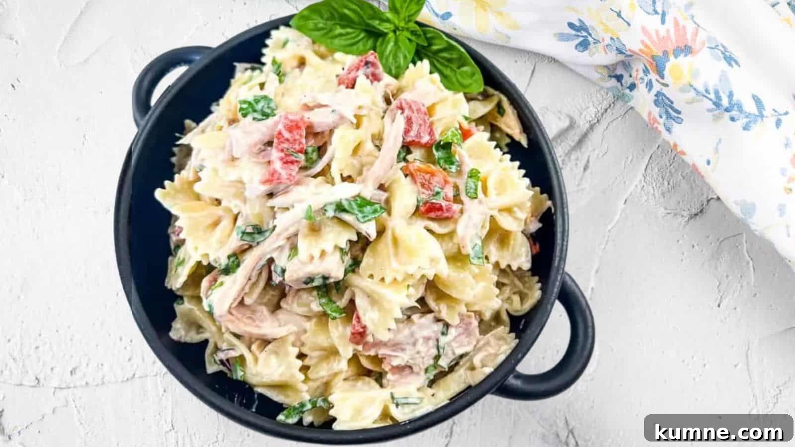 A black bowl filled with rotisserie chicken pasta salad.