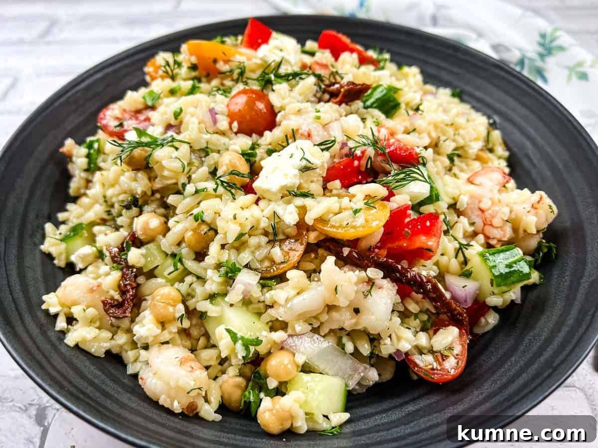 A bowl of Mediterranean orzo salad on a black plate.