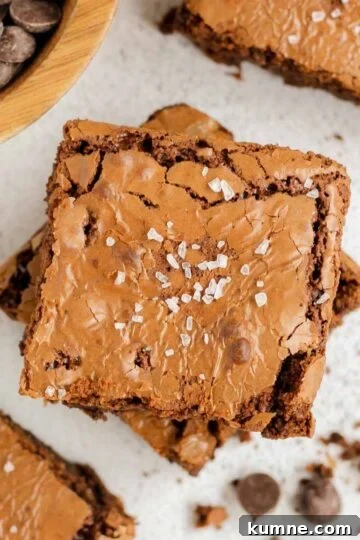 Oat flour brownies sprinkled with sea salt, with crumbs, and a bowl of chocolate chips on the side.