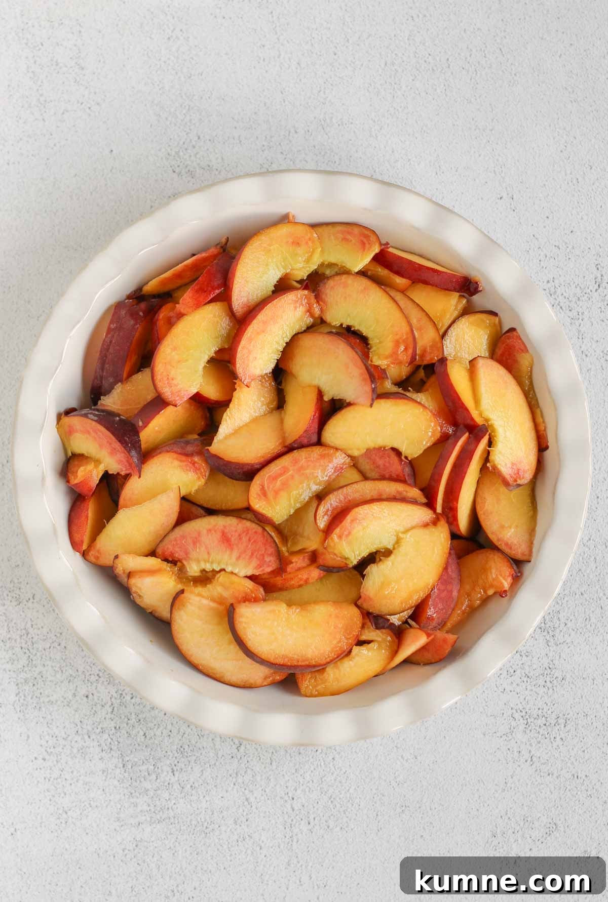 Whole Grain Low-Sugar Peach Crisp Recipe 4 Sliced peaches in a ceramic pie plate.