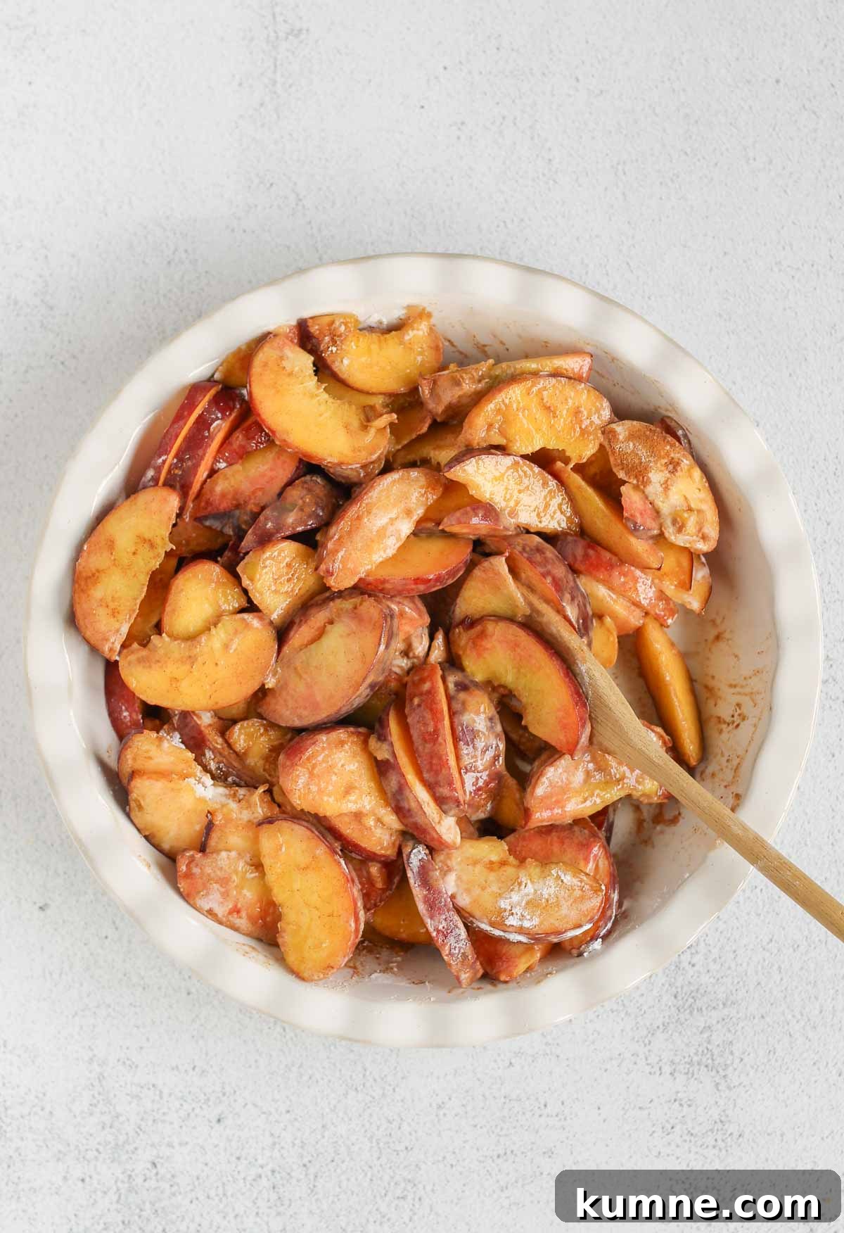 Whole Grain Low-Sugar Peach Crisp Recipe 5 Slice fresh peaches in a ceramic pie dish mixed with cinnamon and tapioca starch.