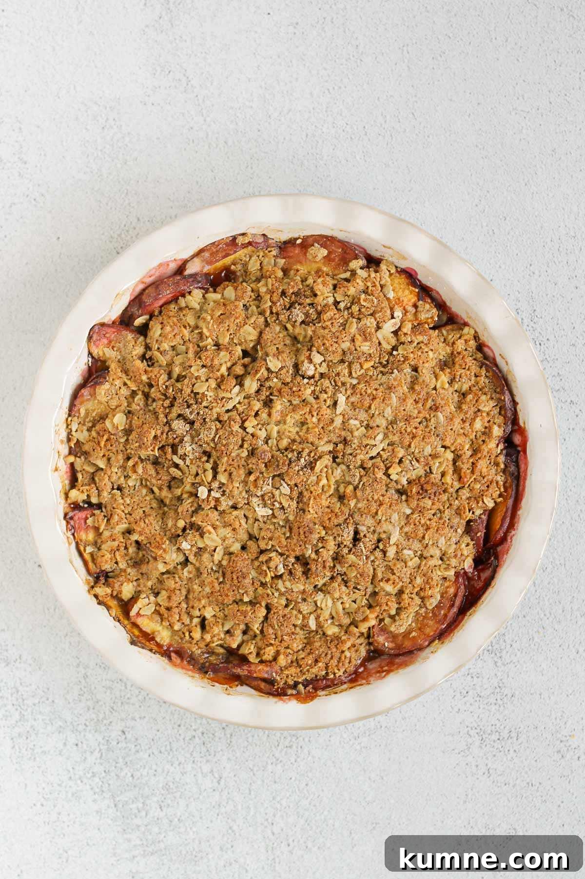 Whole Grain Low-Sugar Peach Crisp Recipe 9 Baked peach crisp in a ceramic pie dish.