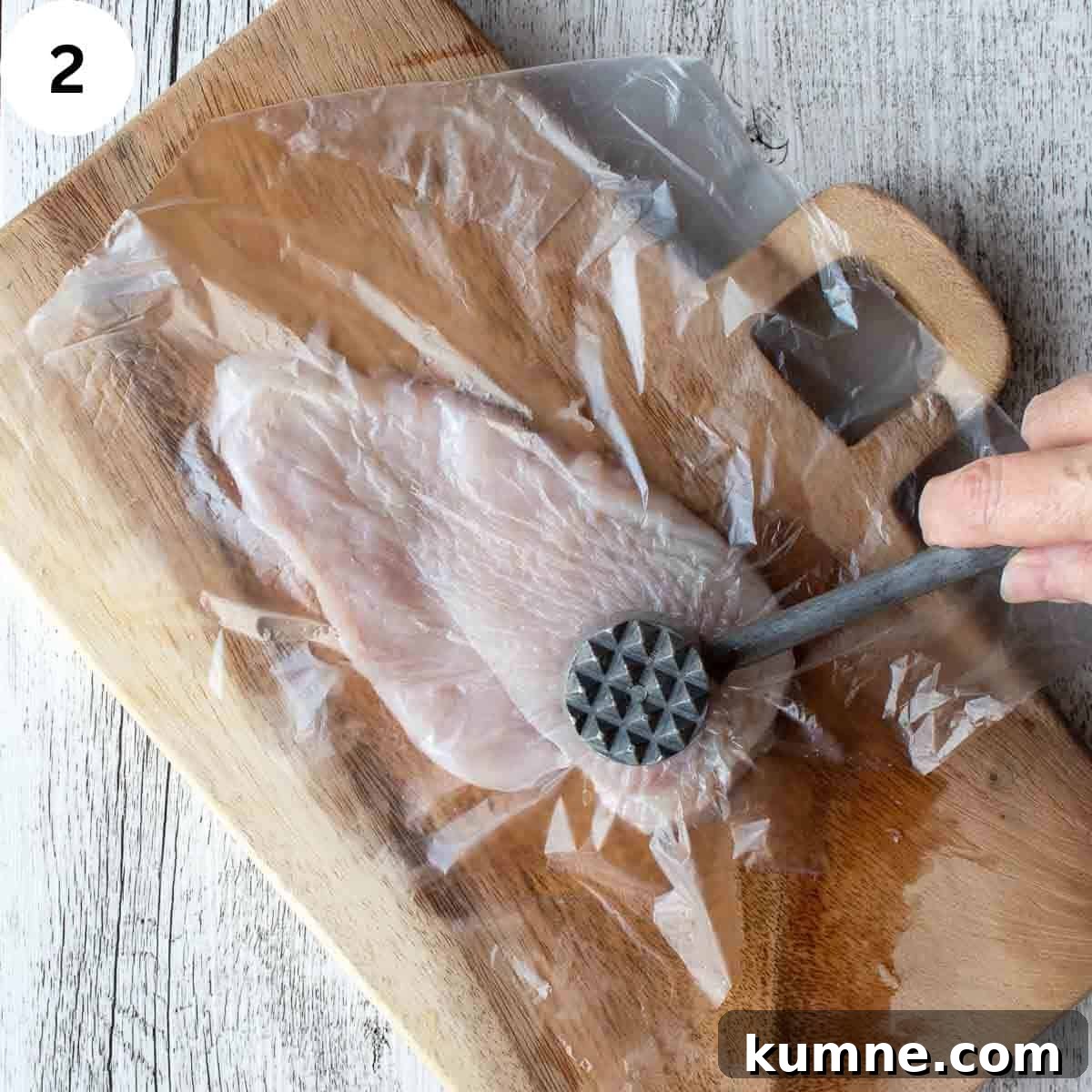 Pounding chicken breast with a meat mallet.