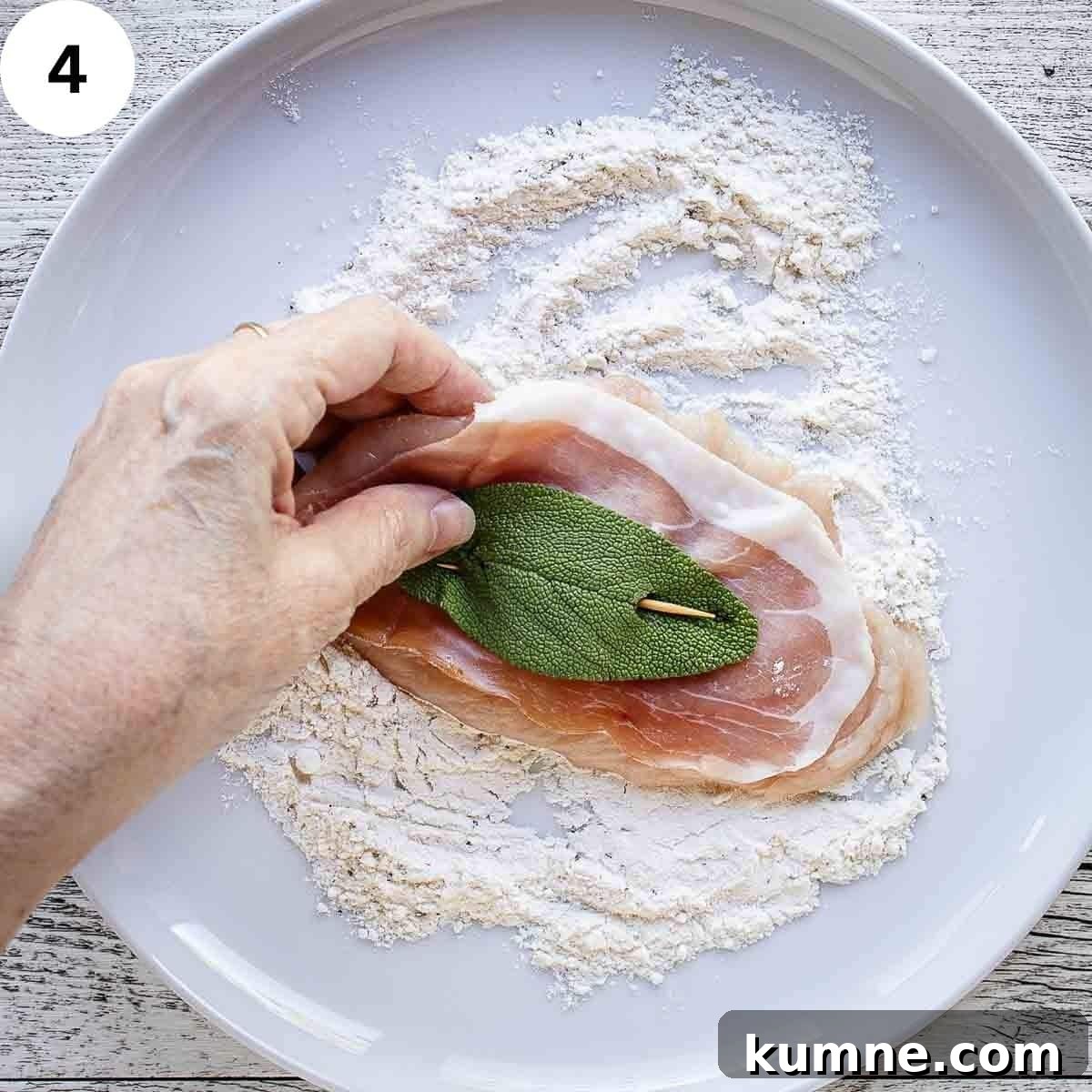Flouring a chicken cutlet that has prosciutto and a sage leaf secured on with a toothpick.