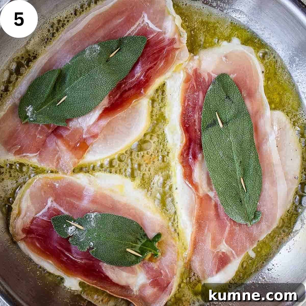 Three chicken cutlets with prosciutto and a sage leaf frying in a pan.