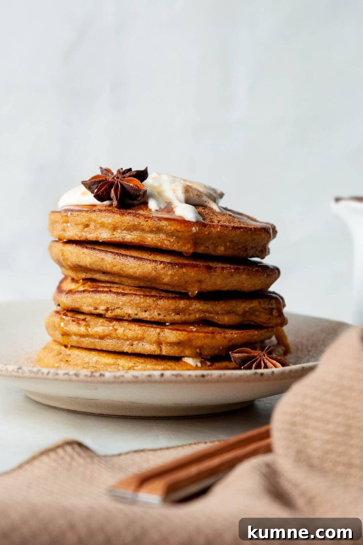 Stack of super fluffy, healthy pumpkin protein pancakes with greek yogurt and maple syrup on top.