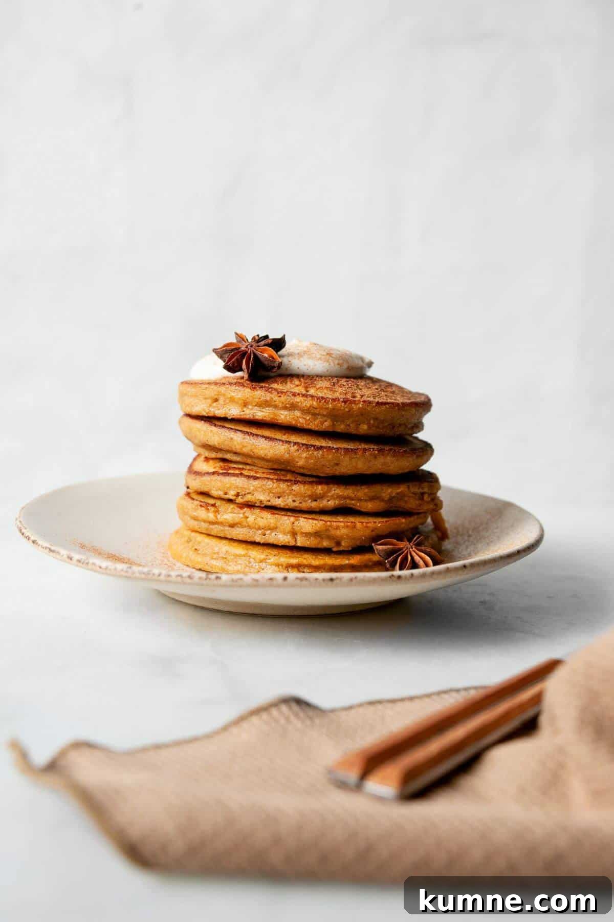 Stack of fluffy blender oatmeal pumpkin protein pancakes on a plate topped with a dollop of Greek yogurt.