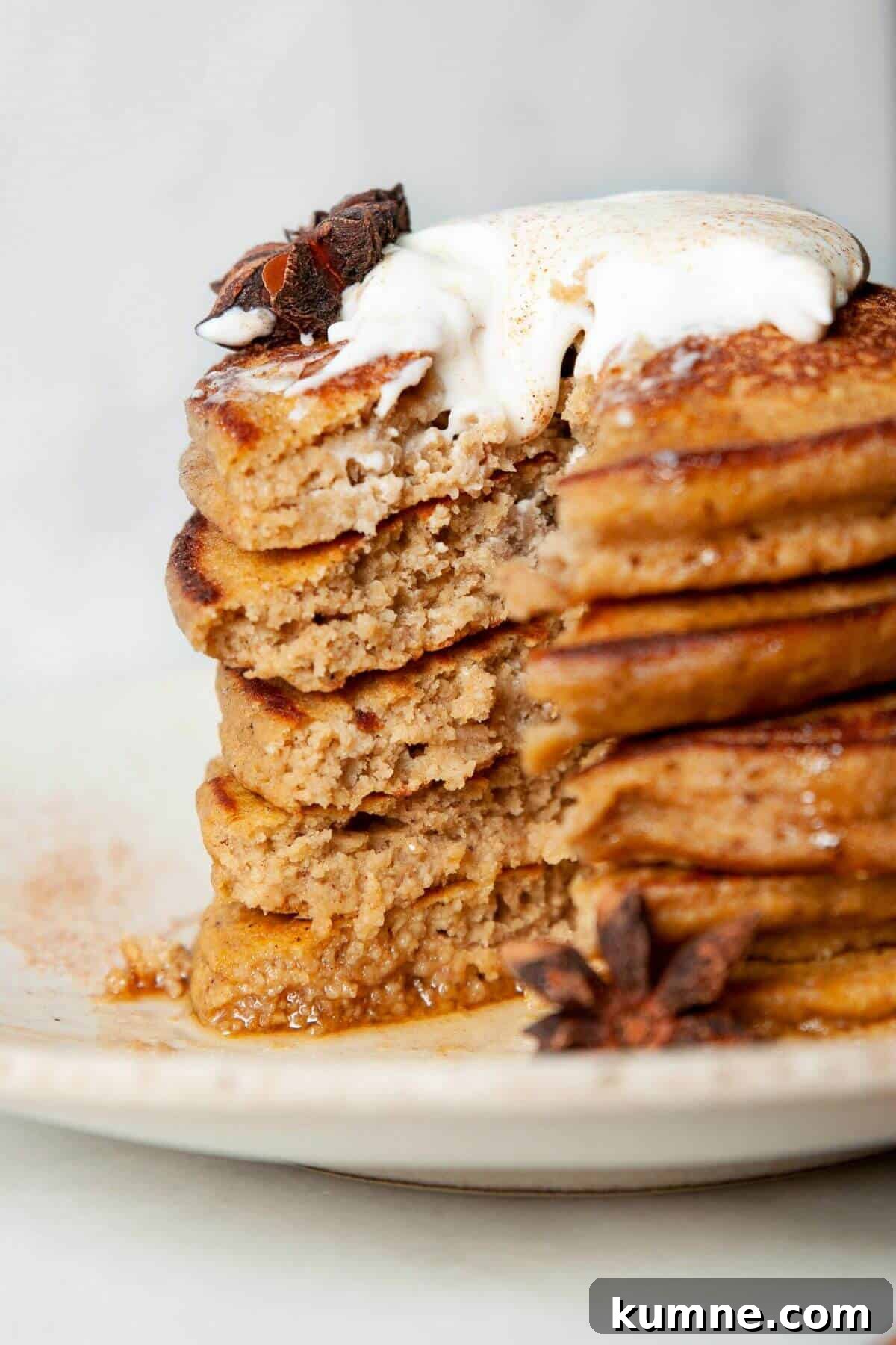 Cutting into a stack of fluffy pumpkin protein pancakes to show soft texture.