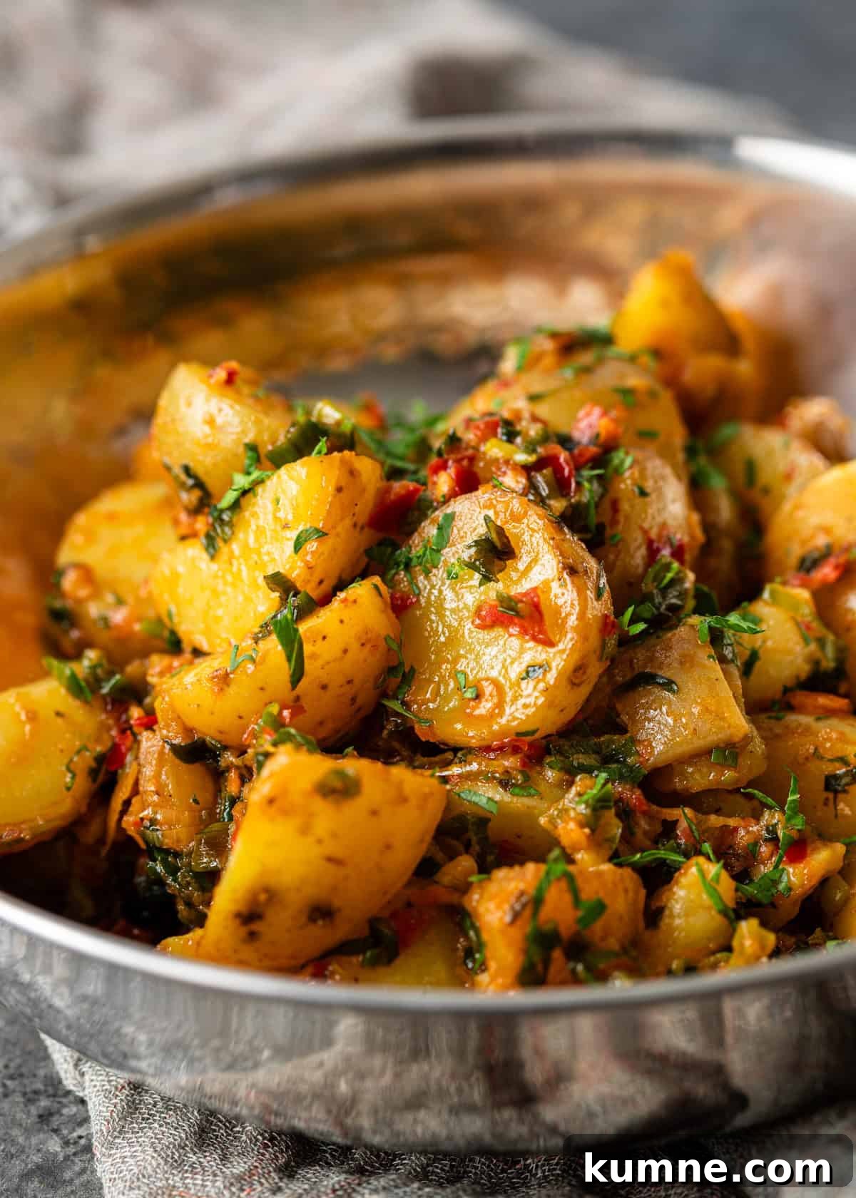 Spicy Calabrian Roasted Potatoes Recipe 9 closeup: calabrian chili potatoes topped with fresh chopped herbs in a metal bowl