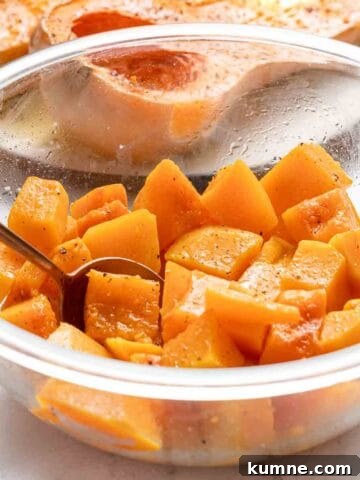 cubes of butternut squash in glass bowl with spoon in bowl.