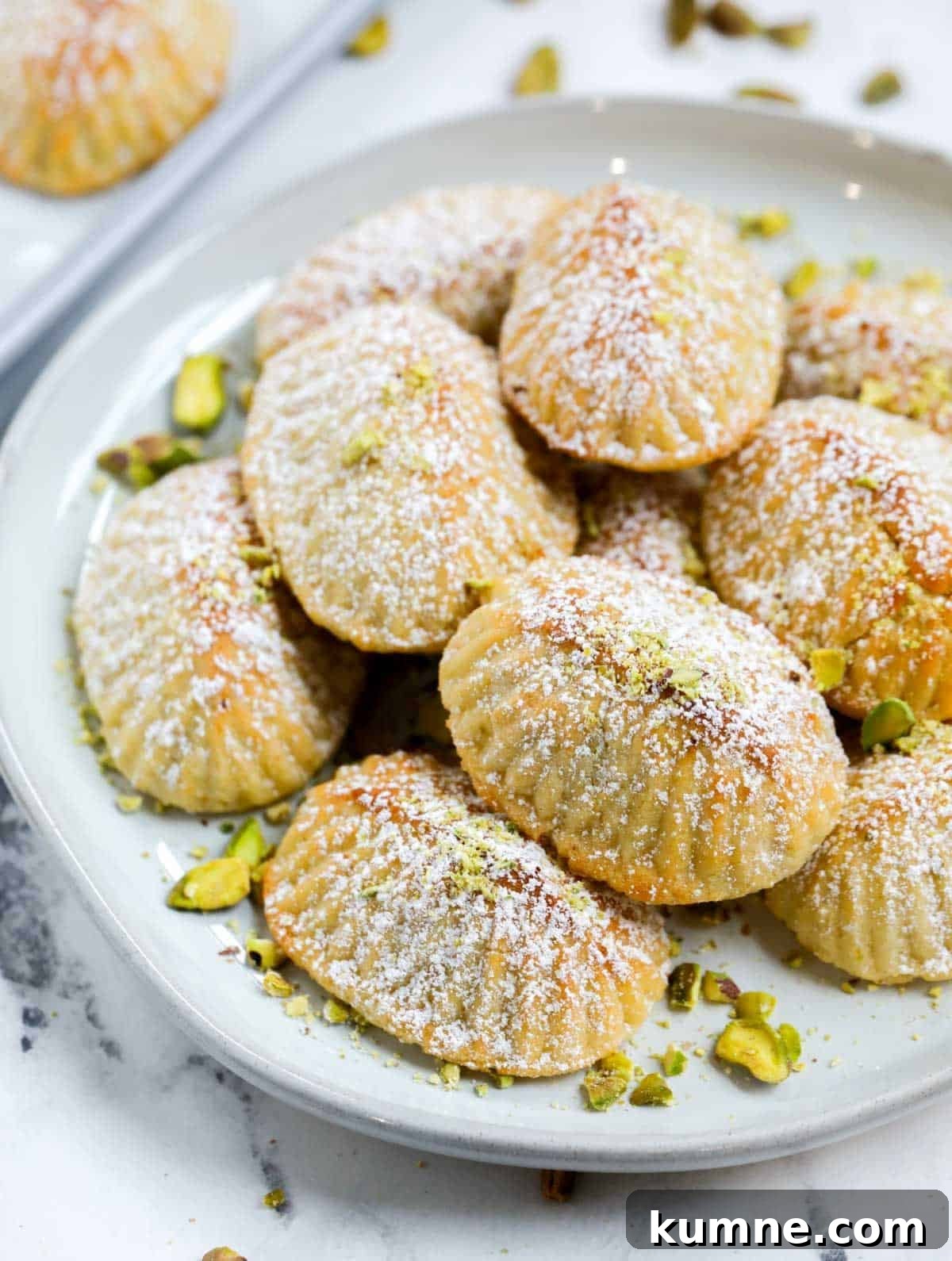 Close up side shot of pistachio maamoul cookies on a plate.