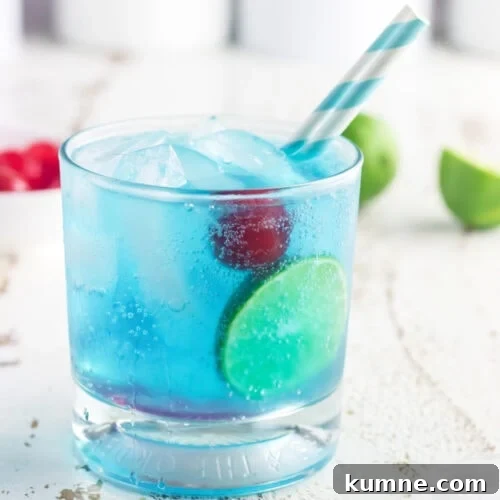 Closeup of a glass of gin and tonic with a cherry in it.