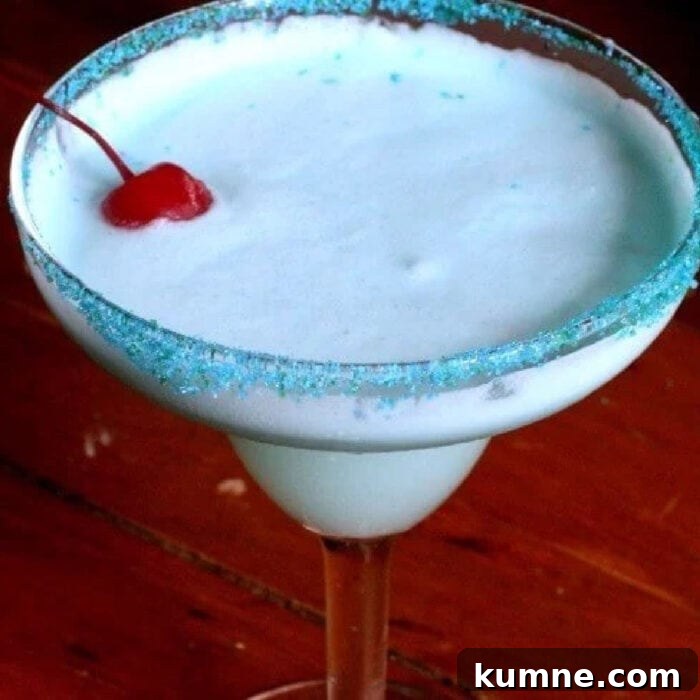 A closeup of a creamy blue cocktail with a cherry on top.