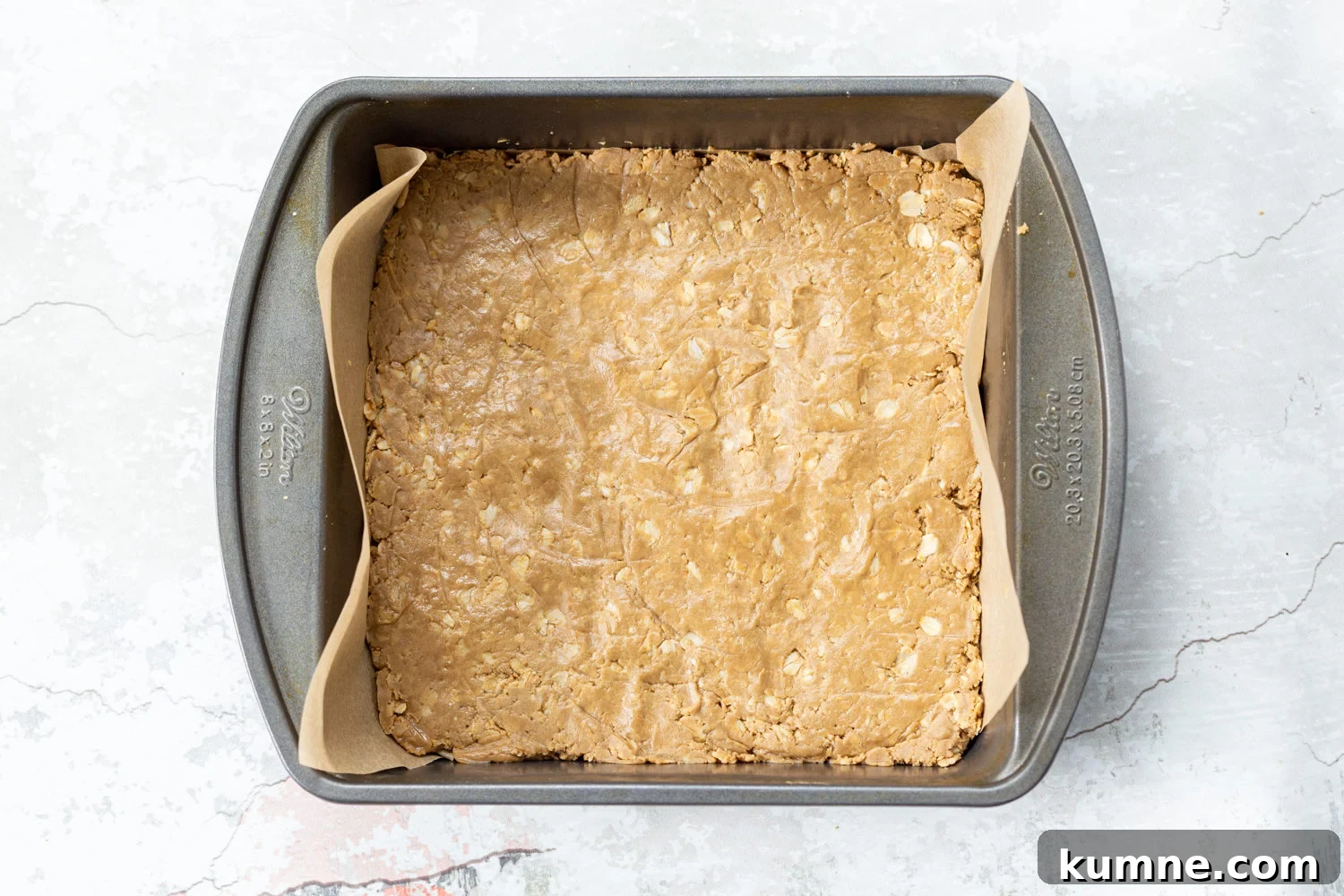 Oats and sunbutter mixture pressed into a parchment lined pan for our Sunbutter Granola bars