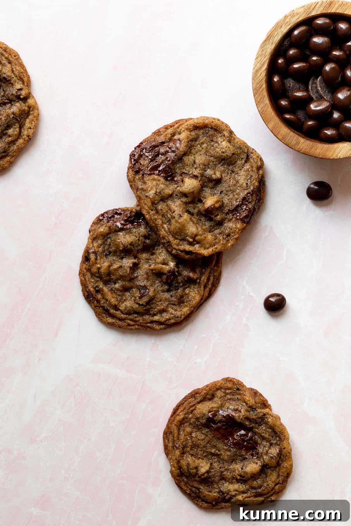 Espresso Chocolate Chip Cookies Recipe for Rich Coffee Flavor 2 espresso chocolate chip cookies on a pink background with a small bowl of chocolate espresso beans