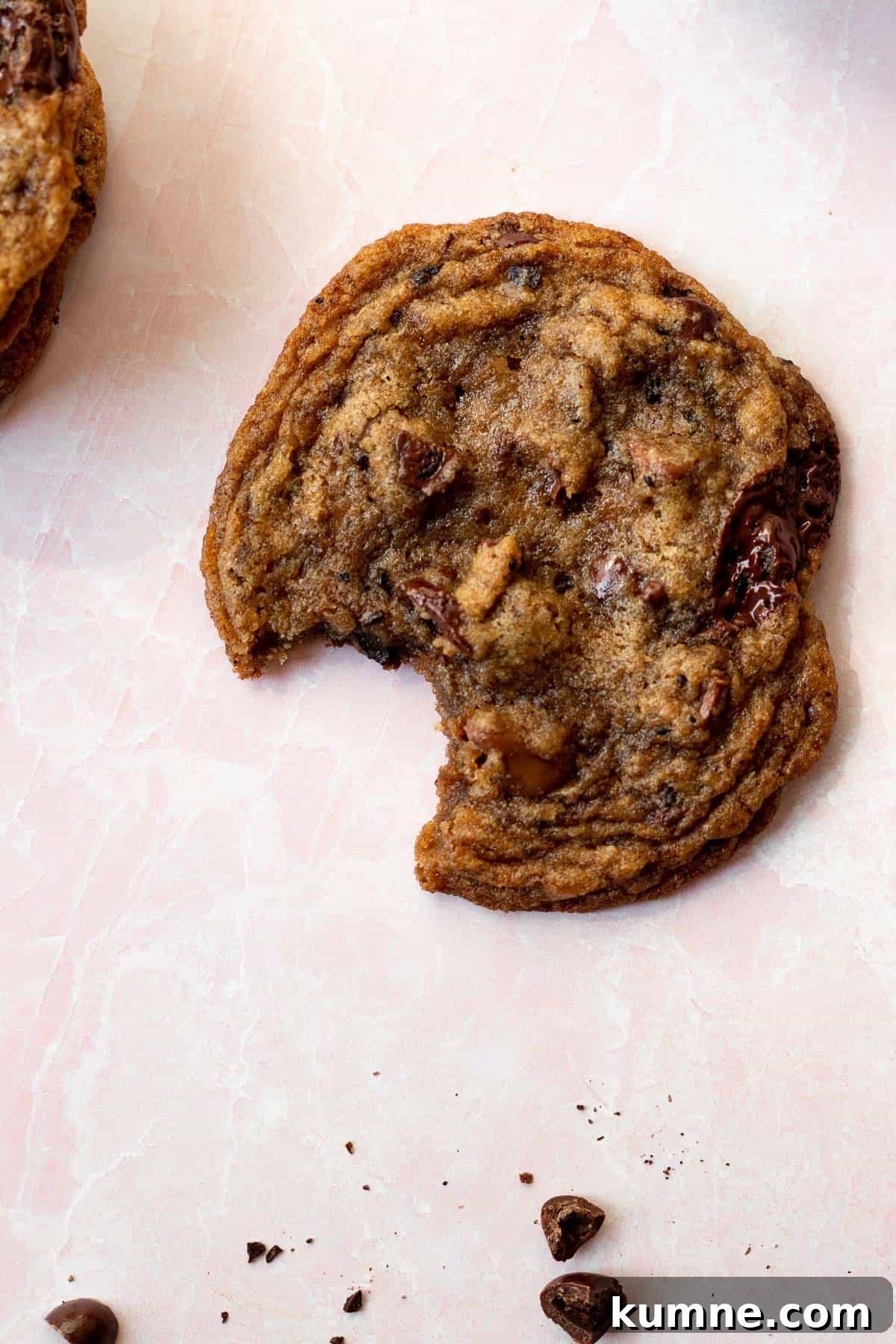 Espresso Chocolate Chip Cookies Recipe for Rich Coffee Flavor 4 espresso chocolate chip cookie with a bite out of it on a pink background with espresso beans