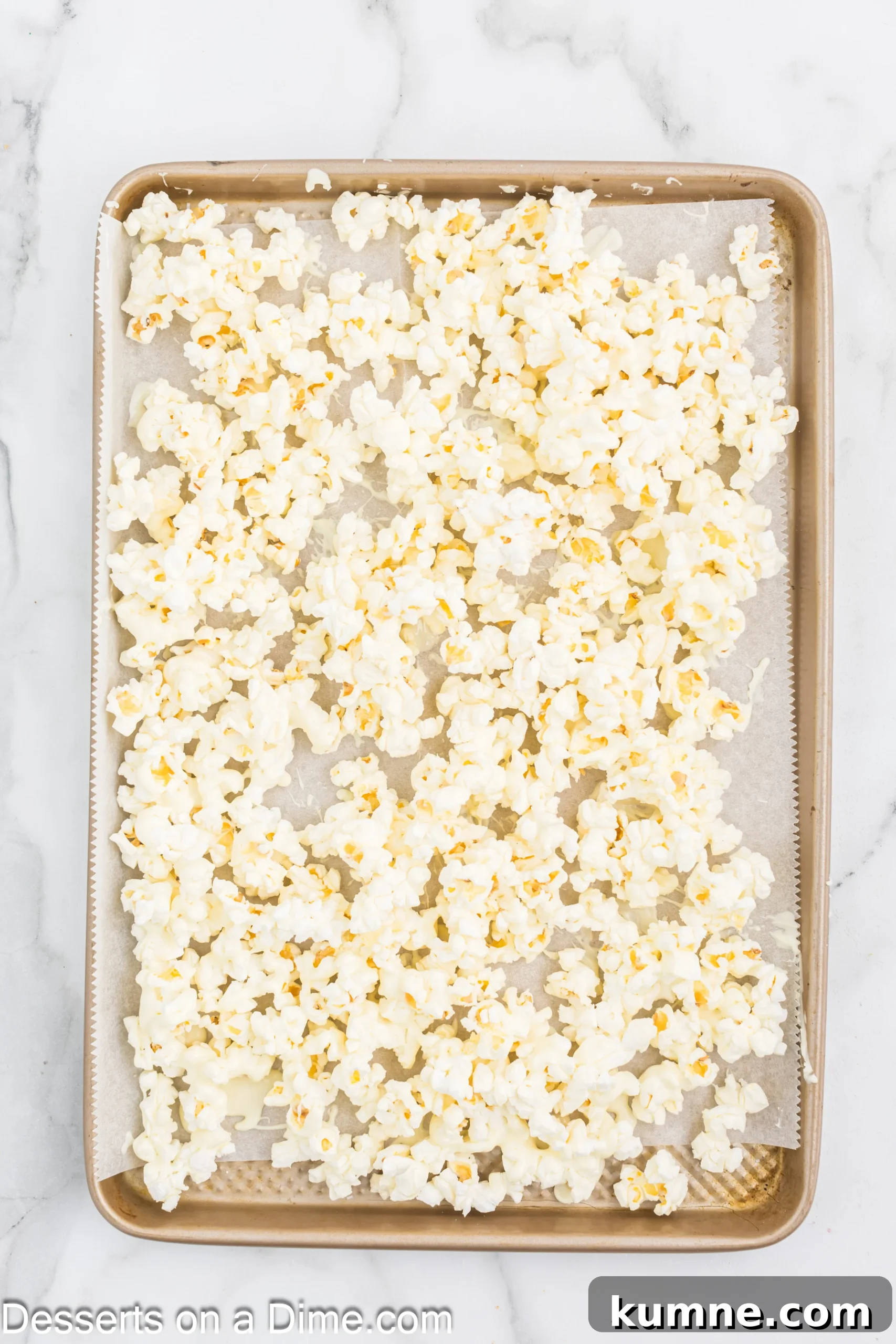 Popcorn topped with melted chocolate on baking sheet.